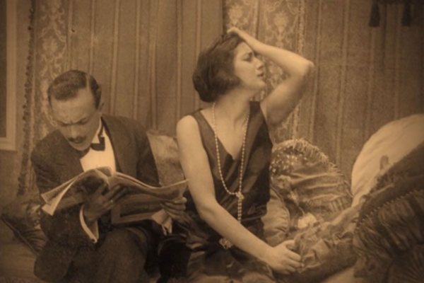 hombre leyendo el periódico y mujer lamentándose