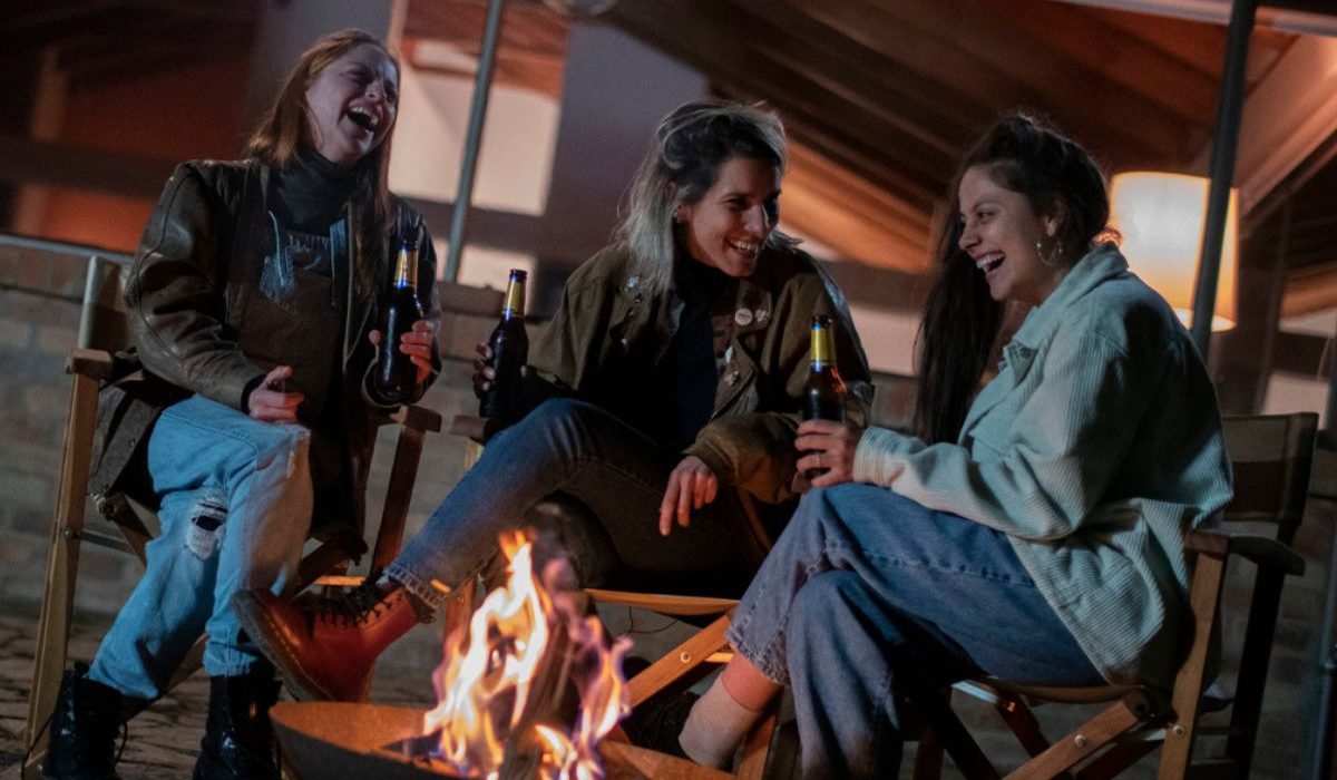 tres mujeres sonriendo alrededor de una fogata
