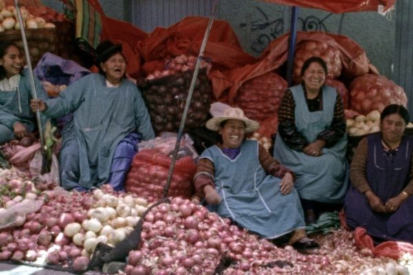 Mujeres campesinas sonriendo y sentadas en bultos de papas